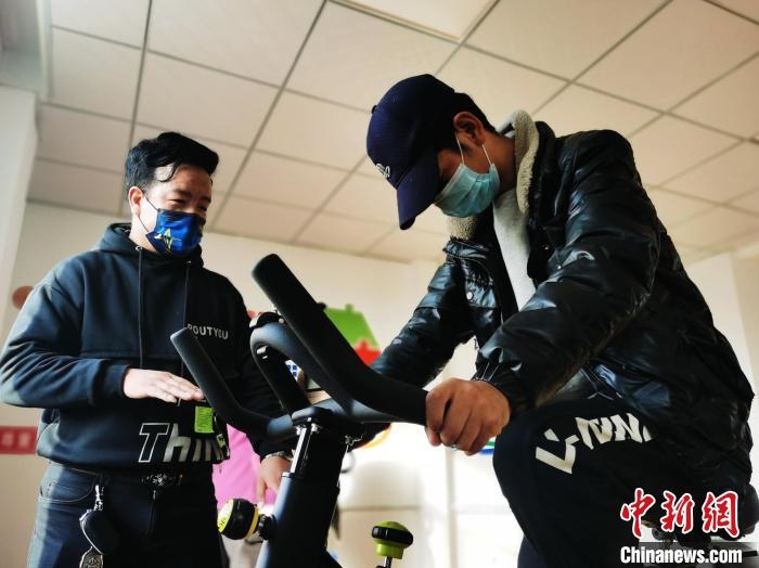 图为尖扎县残疾人托养服务中心负责人张财指导一名残疾人骑动感单车。 张添福 摄 图为尖扎县残疾人托养服务中心负责人张财指导一名残疾人骑动感单车。 张添福 摄