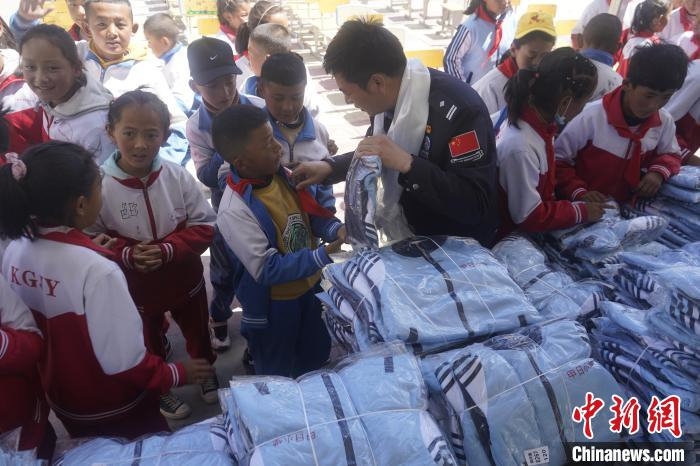 图为拉萨出入境边防检查站的民警为学生发放校服。　贡嘎来松 摄
