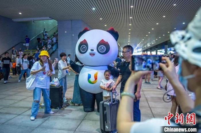 成都東站站臺上乘客與成都大運會吉祥物“蓉寶”合影。　劉忠俊　攝