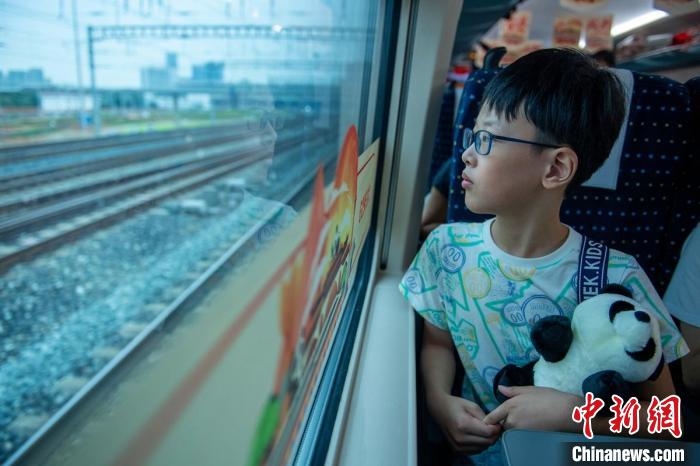 列車啟動后，回香港的郭姓小朋友懷抱著“熊貓”望著窗外。　劉忠俊　攝
